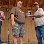 MC Blake Williams looks on as Bill Warren inducts John Bayerl into the Southeast Michigan Bluegrass Music Association Hall of Honor at the 2016 Milan Bluegrass Festival when rain shut down the stage show