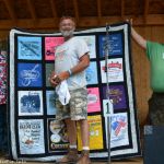 Sound man assistant Mike Page won the handmade quilt raffled off by the Southeast Michigan Bluegrass Music Association at the 2016 Milan Bluegrass Festival - photo © Bill Warren