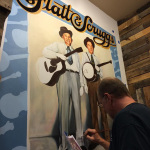 Brian Bain painting Foggy Mountain Breakdown, his portrait mural of Flatt & Scruggs at The Bluegrass Island Store in Manteo, NC