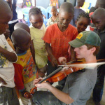 Dan Andree demonstrates fiddle music for a group of orphans in the Congo
