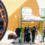 Custom mural being painted on the face of the Elderly Instruments building in Lansing, MI