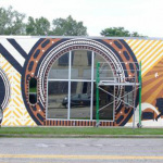 Custom mural being painted on the face of the Elderly Instruments building in Lansing, MI