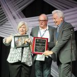 Kitty Kuykendall accepts the Distinguished Achievement Award for Bluegrass Unlimited from Jon Weisberger and Del McCoury at World of Bluegrass 2016 - photo by Frank Baker Union