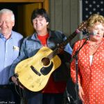 MC Sherry Boyd (right) shows of the autographed guitar to be given away at Palatka Bluegrass Festival, February 2014 - photo © Bill Warren