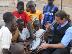 Ben Wright showing his banjo to children in Zinder