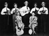 Paul Prince, Lester Flatt, Charlie Monroe, Tex Isley, Birch Monroe; (seated) Gladys Flatt, Helen Osborne