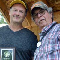 Brian Paige accepts his father, Ralph's, SMBMA Hall of Honor induction from Bill Warren at the 2017 Milan Bluegrass Festival
