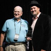 Ted Lehmann accepts for Ernie and Debi Evans during World of Bluegrass - photo by Frank Baker