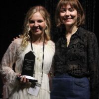 Carly Arrowood accepts her Instrumentalist Momentum award from Molly Tuttle during World of Bluegrass - photo by Frank Baker