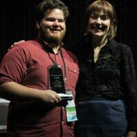 Casey Campbell accepts his Instrumentalist Momentum award from Molly Tuttle during World of Bluegrass - photo by Frank Baker