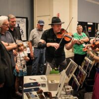David Harvey, Ricky Skaggs, Alan Tompkins, and Larry Gorley watch Mark and Maggie O'Connor in the Exhibit hall at the 2017 IBMA Wide Open Bluegrass festival - photo by Frank Baker