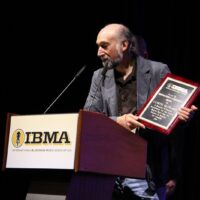 Andy May accepts the Distinguished Achievement Award for Curtis McPeake at the 2018 IBMA Special Awards - photo © Frank Baker