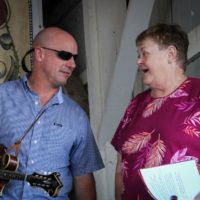 Marc MacGlashan with The Gibson Brothers chats with MC Katy Daley at the 2019 Delaware Valley Bluegrass Festival - photo by Frank Baker