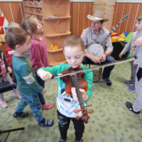 Czech kindergartener try out a fiddle while Petr Brandjes demon starts the banjo at Kindergarten Bludovice