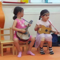 Two Czech girls check out mandolin and guitar at Kindergarten Bludovice