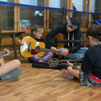 Luke McKnight assists a young guitar student at the 2021 West Virginia State Folk Festival Youth Camp in Glenville, WV