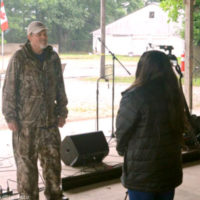 A rain-soaked Wes Pettinger is interviewed by local media at the 2021 Charlotte Bluegrass Festival - photo © Bill Warren