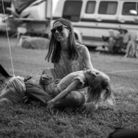 Ellie Brown and her son, River, watch as Maxwell Brown jams under a tent at the 85th Old Time Fiddlers Convention, Galax, VA - photo by Jeromie Stephens