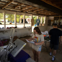 Faith Johnson and Dylan Wall working in the T shirt shop. Saturday September 4th, 2021. Camp Springs, North Carolina - photo by Jeromie Stephens