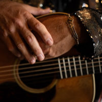 Hands, guitar and bracelet. Gary Brewer of the Kentucky Ramblers at the 50th Dr. Ralph Stanley Hills of Home Memorial Day Bluegrass festival. Coeburn, VA. Thursday May 26th, 2022 - photo by Jeromie Stephens