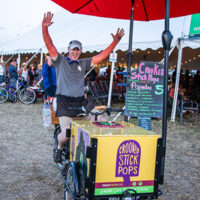 Will Tuman cycling around the festival selling organic, vegan popsicles at the 2022 Grey Fox Bluegrass Festival - photo © Tara Linhardt