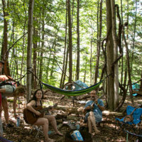 Campers in the shade in their campsite in the woods at the 2022 Grey Fox Bluegrass Festival - photo © Tara Linhardt