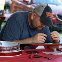 Mike Broadway performs emergency banjo surgery at the August '22 Bluegrass Jamboree - photo by Kristin Yarbrough