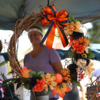 Kim’s Auburn Autumn wreath framed her during Trade Day at the August '22 Bluegrass Jamboree - photo by Kristin Yarbrough