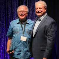 Steve Chandler with his Broadcaster of the Year award with Tim Stafford at the 2022 IBMA Industry Awards luncheon - photo © Frank Baker