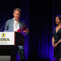 Dan Gabel of PegHead Nation accepts his Distinguished Achievement award from Sharon Gilchrist at the 2022 IBMA Industry Awards luncheon - photo © Frank Baker