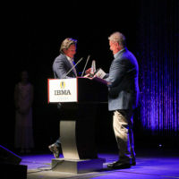 Ronnie Bowman accepts his Songwriter of the Year award from Tim Stafford at the 2022 IBMA Industry Awards luncheon - photo © Frank Baker