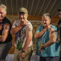 Stage personnel display their Gibson Brothers tattoos at the 2022 Delaware Valley Bluegrass Festival - photo by Frank Baker