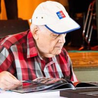 Gary Henderson looking through the new commemorative book at the founders celebration for Bluegrass Country (9/10/22) - photo © Tara Linhardt