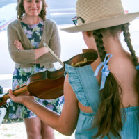 Aynsley Porchak with Tennessee Bluegrass Band admires a young fiddler at the 2023 Abingdon Fiddler's Convention - photo © G Nicholas Hancock