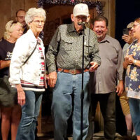 Bobbi and Don Day speak to the audience at the 2023 July Starvy Creek Bluegrass Festival, with new owners Aaron and Amy McDaris - photo by Tammy Harman
