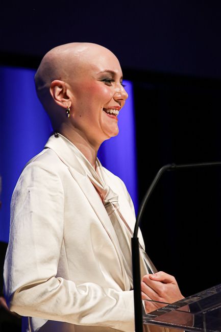 Molly Tuttle accepts Song of the Year and displays her alopecia-based bald head at the 2023 IBMA Bluegrass Music Awards - photo © Frank Baker