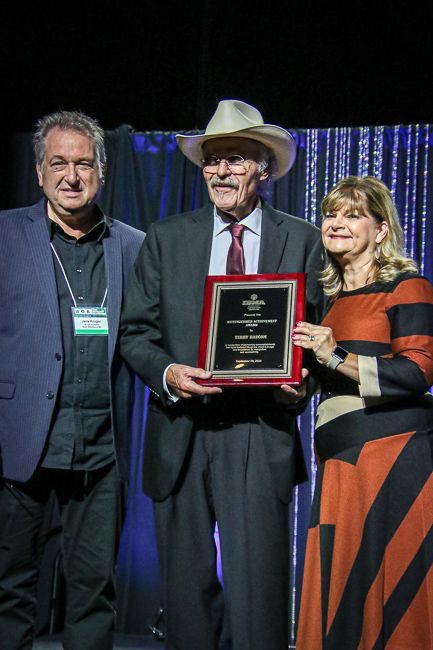 Jens Kruger, Terry Baucom, and Cindy Baucom as Terry accepts his Distinguished Achievement Award during the 2023 IBMA Industry Awards - photo © Frank Baker
