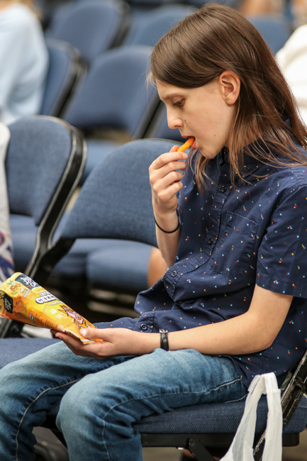 Fiddler Alexander Ferranti studies Cheetos package at Kids on Bluegrass - IBMA 2025 - photo © G. Nicholas Hancock