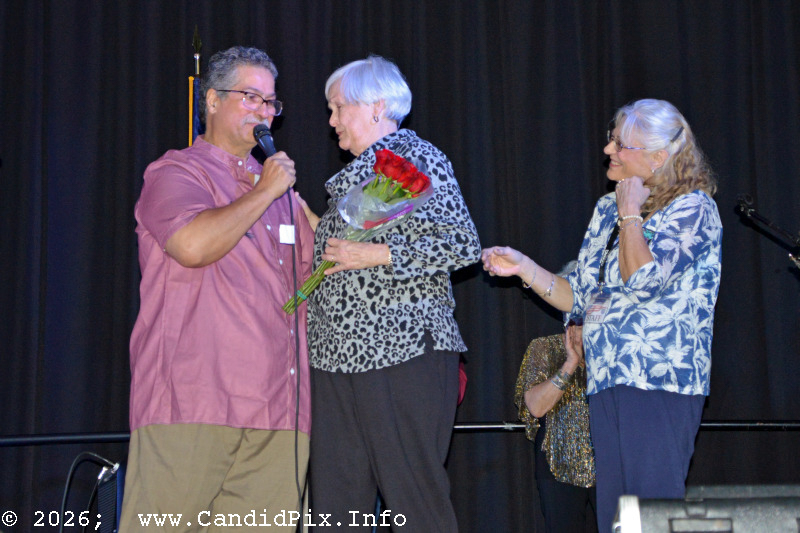 Ernie and Debi Evans present a bouquet of roses to former promoter Judy Adams at the 2026 Jekyll Island Bluegrass Festival - photo © Bill Warren