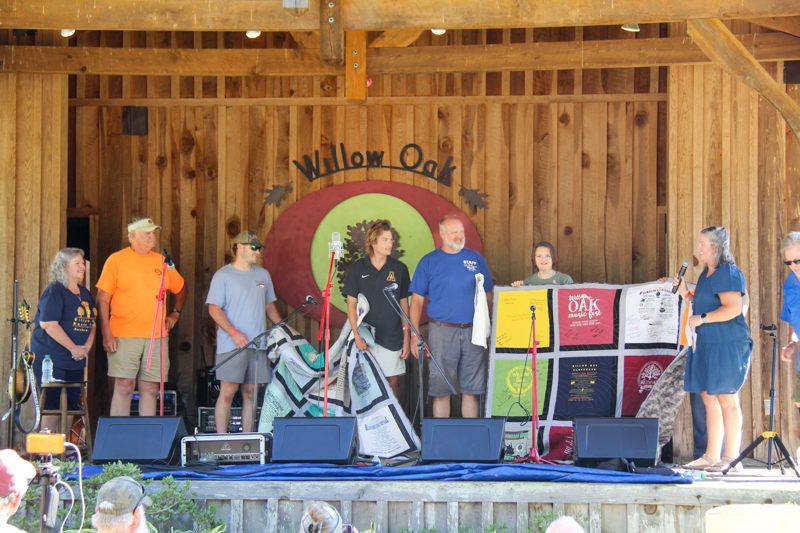 Promoter Mike Wilson receives a custom quilt from his family at the 2026 Willow Oak Bluegrass Festival - photo © Laura Ridge