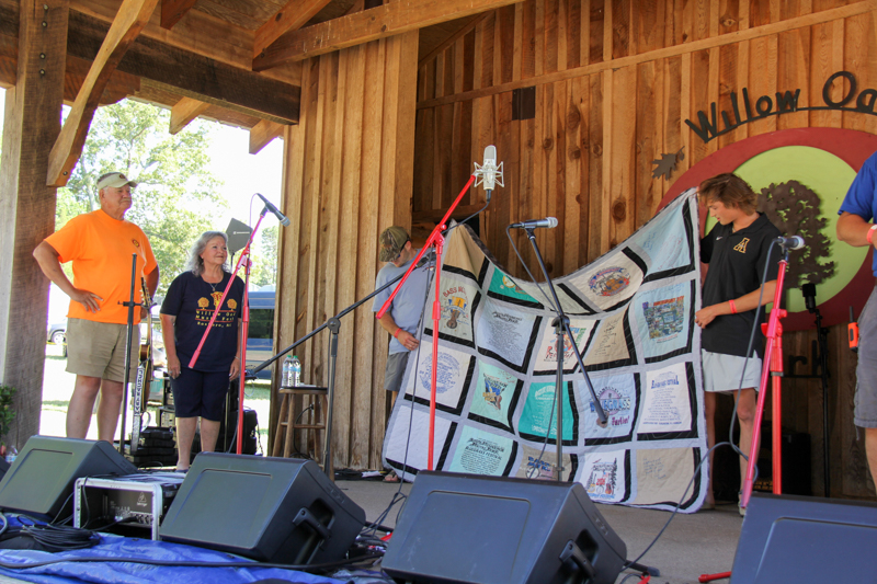 Promoter Mike Wilson receives a custom quilt from his family at the 2026 Willow Oak Bluegrass Festival - photo © Laura Ridge