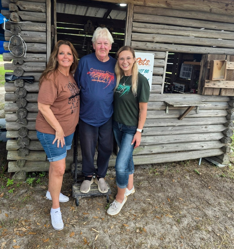 Gate assistant Molly Moore, campground owner Sharon Crawford, and Lorraine Jordan's daughter, Susanna Langdon, at the 2026 Twin Oaks Bluegrass Festival