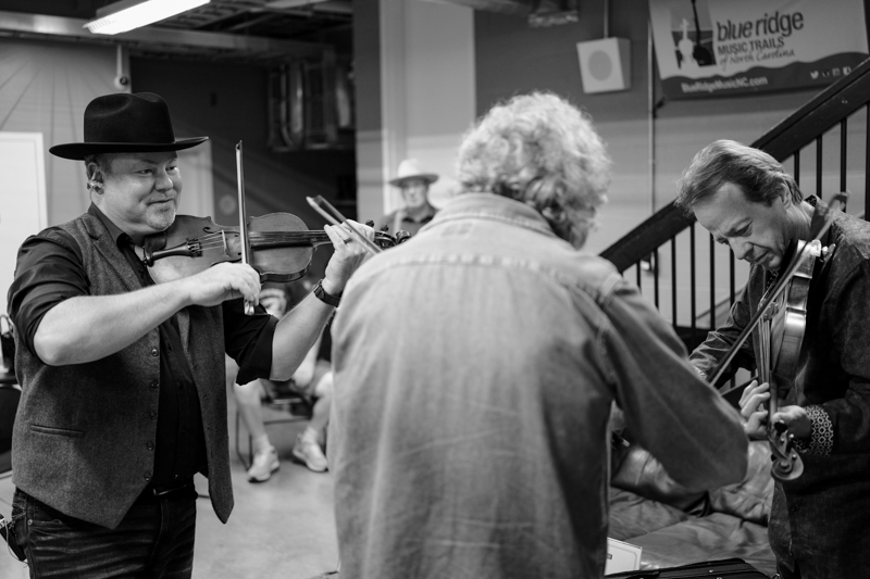 Jim VanCleve, Sam Bush, and Stuart Duncan warm up backstage at the 2026 National Fiddler Hall of Fame induction - photo © Jamey Booher Photography